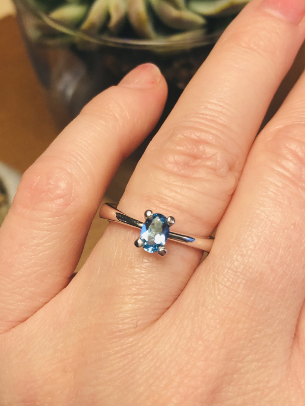 Sølvring med oval lyseblå topaz på finger closeup