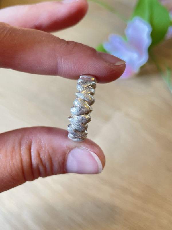 Hjertering i sølv holdt imellem fingre